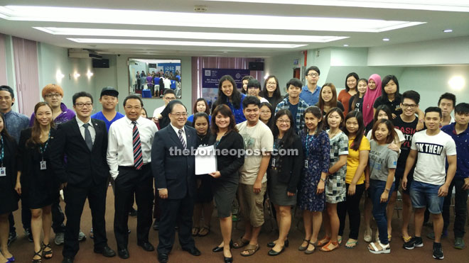 Lau (eighth right) and Chin (fourth left) in a group photo with students after the signing and exchange of documents ceremony. 