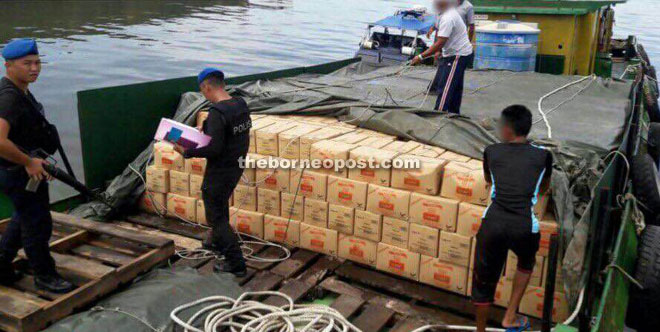 Marine police inspecting the 1,200 packs of cooking oil that were seized. 