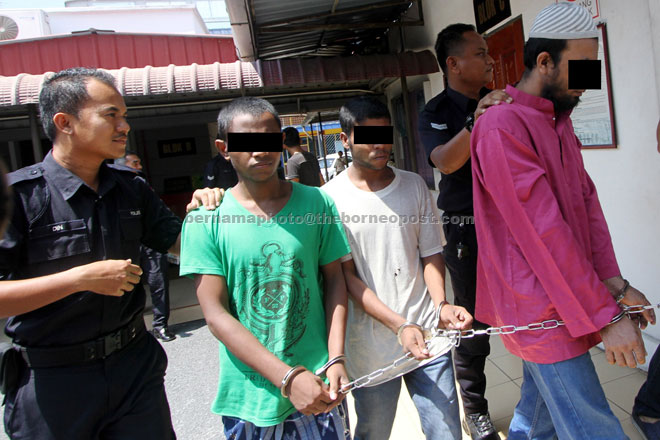 Three of the four foreigners being brought out from the court room after they were charged with trafficking of migrants at Wang Kelian. — Bernama photo