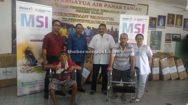 Syed Mohd Faidz (second left) presenting the UWalkers to the Hotspring Old Folk home, received by Taufiq (third right), while Yahya (standing on the UWalker on the right) and Kasmo (left) and others look on.