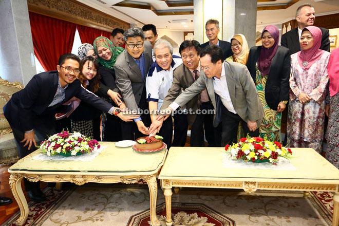 Awang Tengah (fifth left) together with Ministry of Resource Planning and Environment permanent secretary Datu Sudarsono Osman (fourth left) and some staff cutting a cake during a simple farewell gathering. — Photo by Muhammad Rais Sanusi