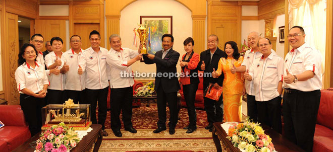 Musa (right) and Goh holding the trophy while Wong (sixth right), Chua (fifth left), Shim (fourth right) and others look on. 