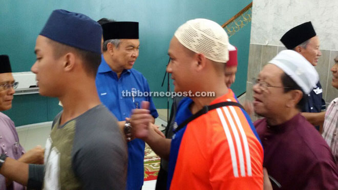 Zahid (second left) shakes hand with the people after the prayer.