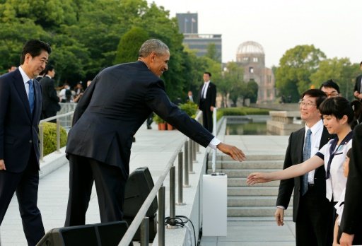 US President Barack Obama (C) greets a school student as Japanese Prime Minister Shinzo Abe watches (L) after laying wreaths for victims of the atomic bombing in 1945, at Hiroshima Peace Memorial Park. Photo by AFP