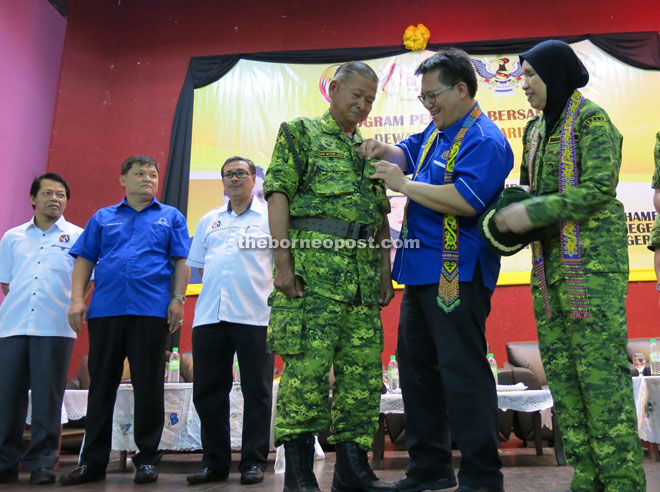 Jazlan (second right) pins a badge onto a Rela member as (from right) Kamariah, Dr Anthony, Huang and Khalid look on.