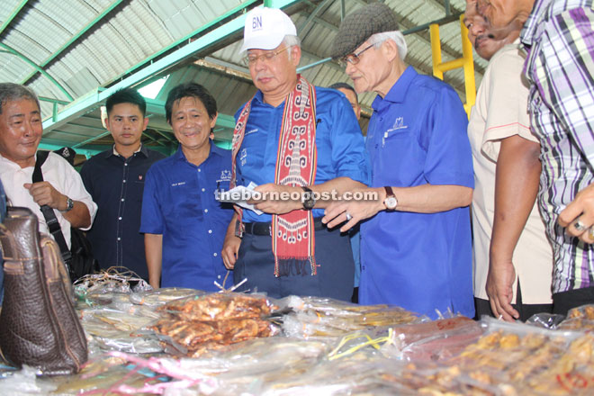 Najib (fourth left), flanked by BN candidate for Krian, Kilat Beriak (third left) and BN candidate for Krian, Datuk Abdul Wahab Aziz, purchases some processed seafood at a hawker’s market during his walkabout.