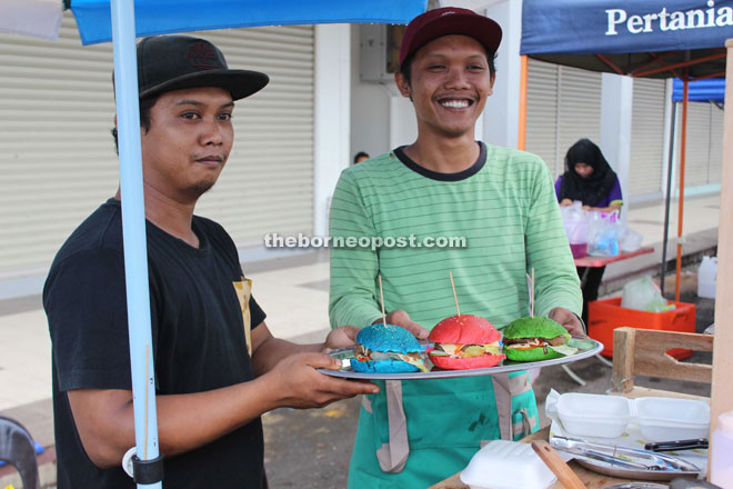 Saiful and his assistant showing his coloured burger offerings.