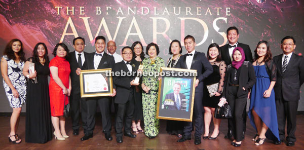 Aisah Eden (centre) posing with the award and the BrandLaureate Business World Review cover at The BrandLaureate Awards. 