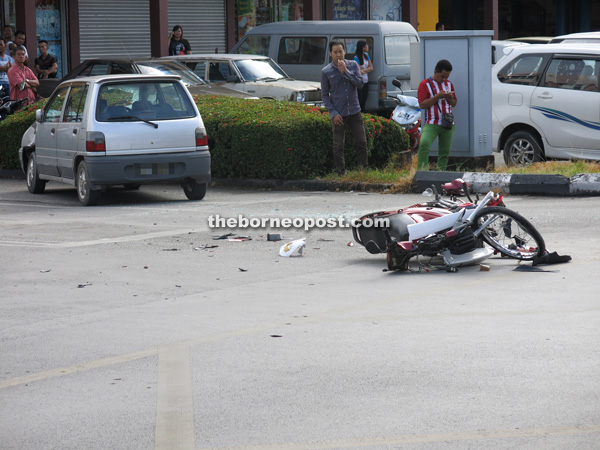 The damaged motorcycle and dented Kancil at the scene of the accident.