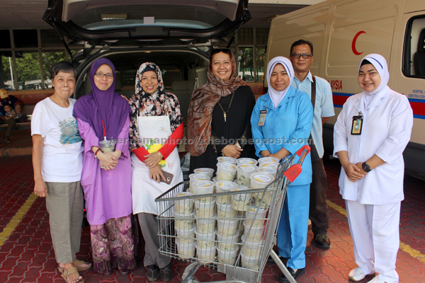 National Cancer Society Malaysia (NCSM) Pink Unity president, Lena Abdullah (centre), presents free ‘Bubur Lambuk’ prepared by cancer survivors to Hospital Kuala Lumpur’s paediatric oncologist, Dr Ida Shahnaz (second, left) to be distributed to patients and staff of Paediatric Department, on Tuesday for ‘buka puasa’. — Bernama photo