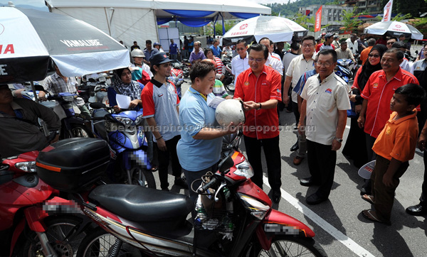 Liow checking motorcyclist helmet after launching the ‘Focus on the road not on the hand’ slogan after officiating the Road Safety campaign in conjunction with coming Hari Raya celebration. — Bernama photo