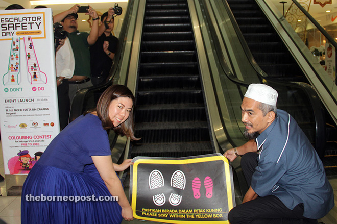 Mohd Hatta (right) and Datin Christine Ling placing a safety sign at the foot of an escalator 