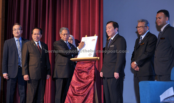 Mustapa (third left) signs a copy of the MITI Report 2015 yesterday during its launch while other ministers and MITI board members look on. — Bernama photo  