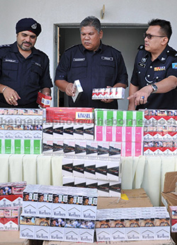 Marzuki (centre) shows the seized cartons of contraband cigarettes during the press conference. — Bernama photo