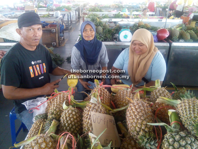 (From left) Ahmad, Azinah and her sister Hasinah Abu Bakar at their pineapple stall at Sarikei Wet Market.