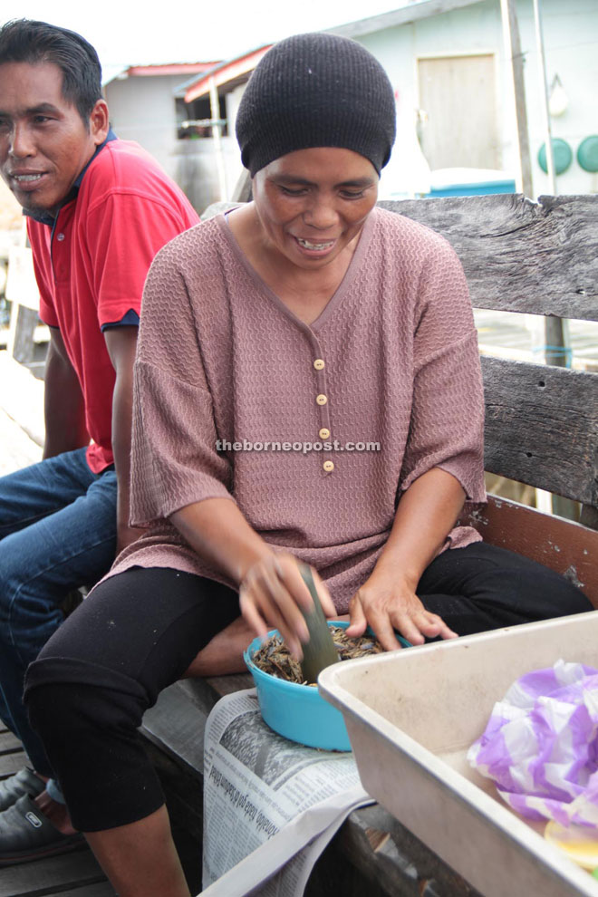 A villager pounds the smoked fish to be made into Sambal Ikan Tahai.