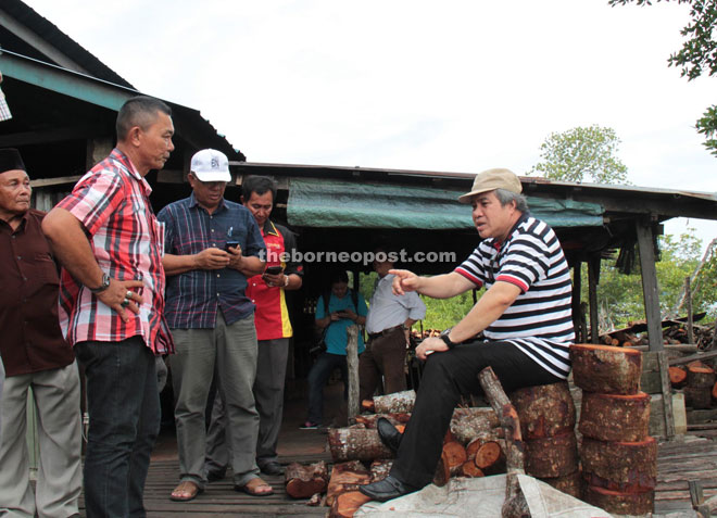 Awang Tengah at home sitting on a stake of cut Bakau wood, discussing with Awangku Tajudin (left) and the villagers on plans to rebuild four smokehouses in Kampung Punang.