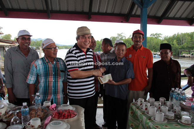 Awang Tengah (third left) hands over a RM200,000 cheque to a village representative for the repair of jetty in the village. He also pledged to support redevelopment of four Ikan Tahai smokehouses in Kampung Punang.