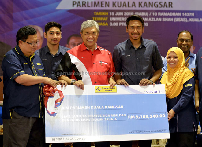 Ahmad Zahid presents a replica of a cheque to Amanah Ikhtiar Malaysia director Kuala Kangsar branch Rosnani Abdul Rahman (right) during the gathering. — Bernama photo