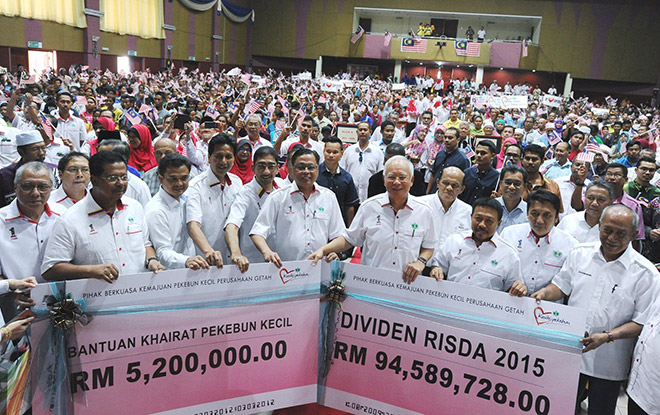 Najib (front third right) and others showing the replica cheques for the dividend and death benefits. — Bernama photo