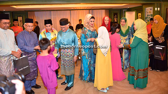 Taib (fourth left) and Ragad (fifth left) present Hari Raya gifts to children at the event. Talip is at second left. — Penerangan Photo.