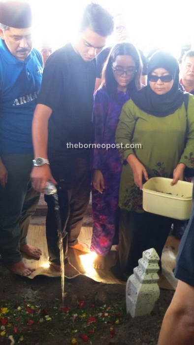 Relatives perform funeral rites over the grave.