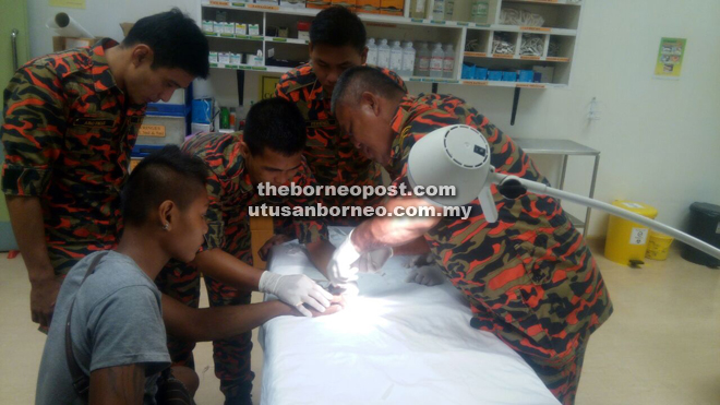 Firemen use a ring cutter and saw to free the patient’s swollen finger from the steel ring. — Photograph courtesy of Bomba Sarikei