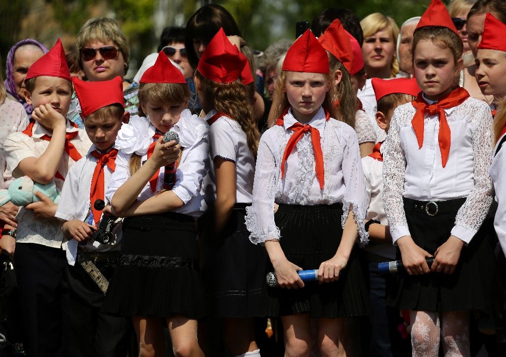 Children in red caps and ties, inspired by the Soviet 'Pioneers' movement, take part in a meeting of the youth movement 'Patriot', an organization of the self-proclaimed People's Republic of Donetsk, on the outskirts of Donetsk. Photo by AFP