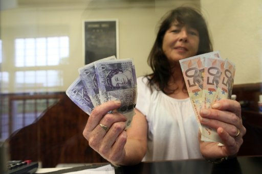 Delia Breen, who works in a money exchange office at the border between Northern Ireland and the Republic of Ireland in Dundalk, holds up handfuls of sterling notes and euro notes on June 7, 2016 by Douglas Dalby | AFP photo