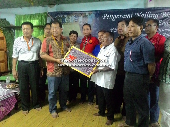 Tuai Rumah Panggau Jugah hands over a souvenir to Ugak (second from left, front row).