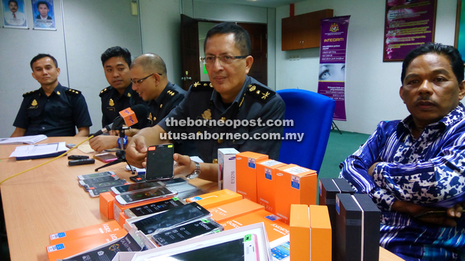 Abdul Hafidz (second right) showing reporters one of the counterfeit Samsung smartphones during the press conference.