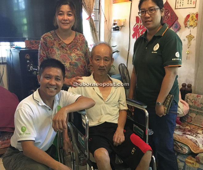 Wan (left) and Law (right) handing over the wheelchair and milk powder to Lim (in wheelchair).