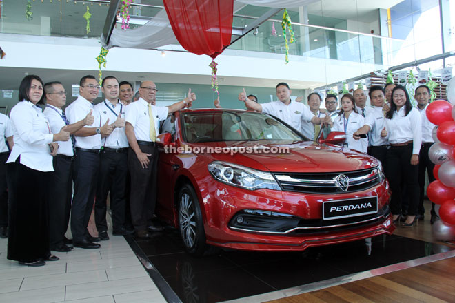 Proton Edar Sdn Bhd area manager Ahmadi Abdul Latif (third left, front row), sales manager Jeremy Chan (fifth right, front row) and staff giving the thumbs-up to the new Perdana.  