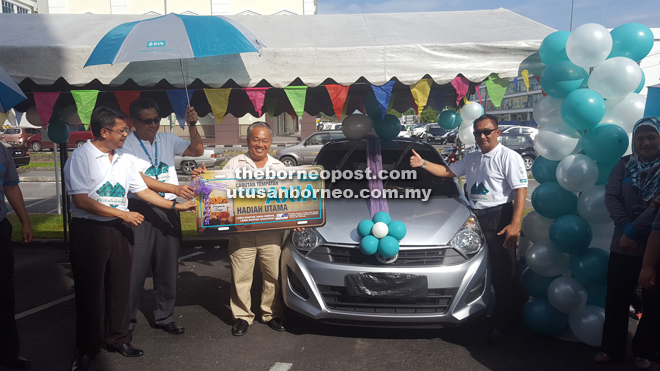 Kong (third left) proudly shows off his win, a Perodua Axia car. Also seen is Zamri (right) and other BSN officers.
