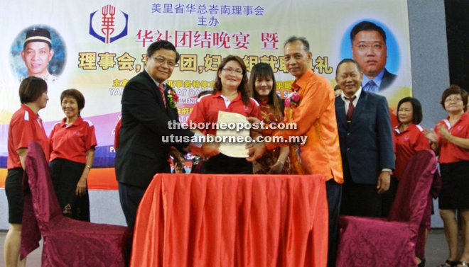 Chairperson of the association’s women’s wing Huong Kue Ing receives her appointment letter from Penguang and Hii.