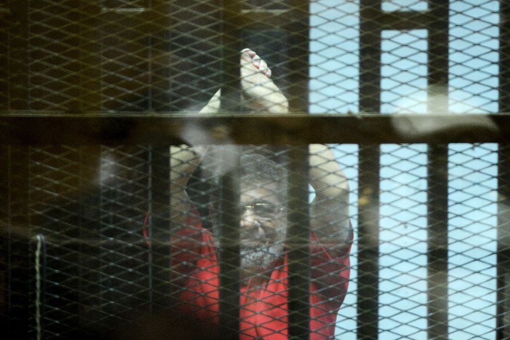 Egypt's ousted Islamist president Mohamed Morsi gestures from behind the defendant's bars during his trial on espionage charges at a court in Cairo on June 18, 2016. Photo by AFP