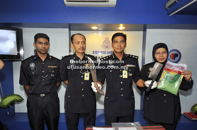 Chandra (second left) showing the weapons seized from the robbery suspects.