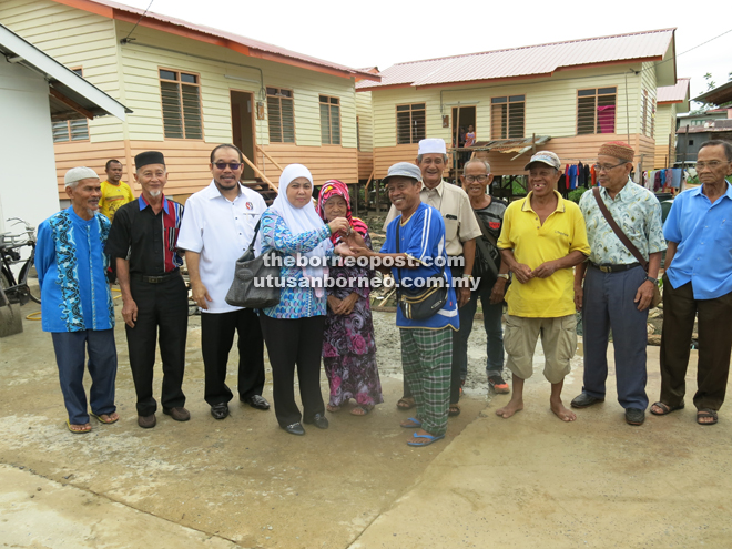 Norah (fourth left) handing over the house keys to one of the fire victims as Mastapa (third left) and others look on.