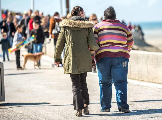This file photo shows a woman walking with an overweight person in Berck-sur-Mer, northern France. Being overweight shaves about a year off a person’s life expectancy, a heavy price which soars to about 10 years for the severely obese, a large-scale study. — AFP photo