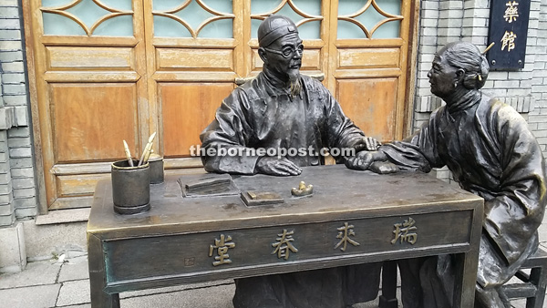 Bronze statues at the street of Three lanes and Seven alleys of a Chinese doctor listening to the pulse of his patient.