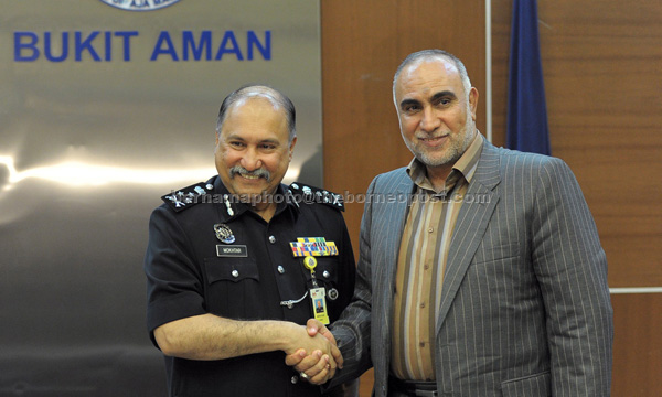 Mohd Mokhtar (left) shakes hand with M Mirzaei at at the federal police headquarters in Bukit Aman. — Bernama photo