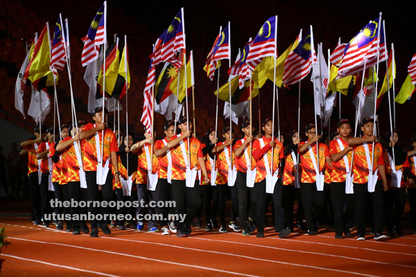 SEDIA: Kontinjen membawa bendera semasa raptai penuh perasmian SUKMA XVIII di Stadium Sarawak, malam kelmarin.