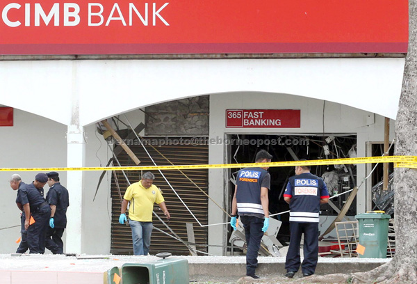 Police officers looking for clues at a bank in Muadzam Shah. — Bernama photo