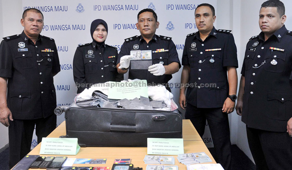 Wangsa Maju District police chief Supt Mohamad Roy Suhaimi Sarif (centre) showing the items seized during an operation against ‘African Scam’ in Kuala Lumpur. — Bernama photo