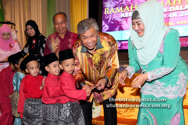 DUIT RAYA: Ahmad Zahid (dua kanan) bersama isterinya, Datin Seri Hamidah Khamis (kanan) menyerahkan duit raya kepada anak-anak yatim pada Majlis Ramah-Tamah KDN Sarawak, semalam. Turut kelihatan Masir (tiga kanan).