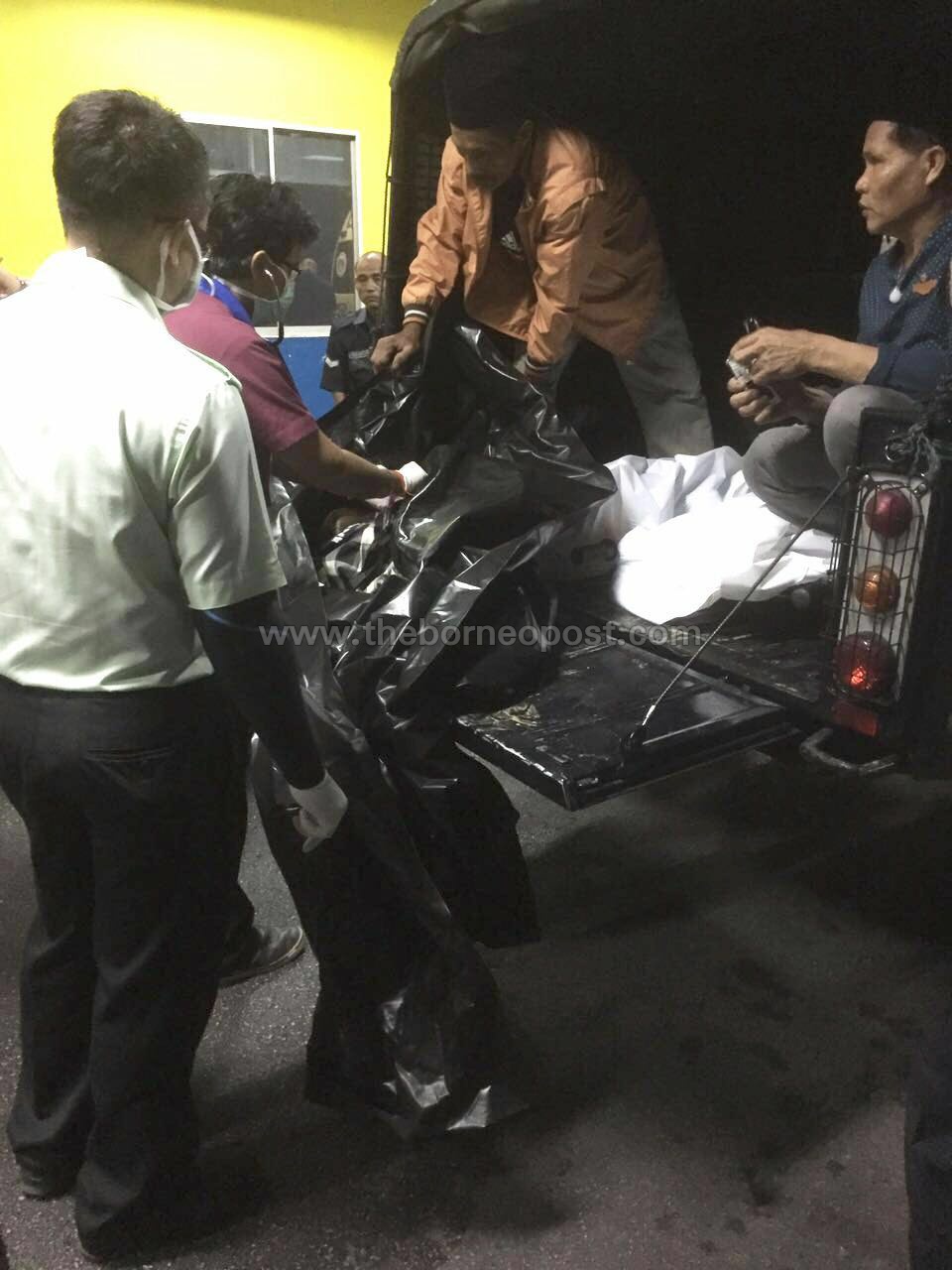 A doctor inspects the deceased mother and two children after their bodies were brought to the Sarawak General Hospital by police.