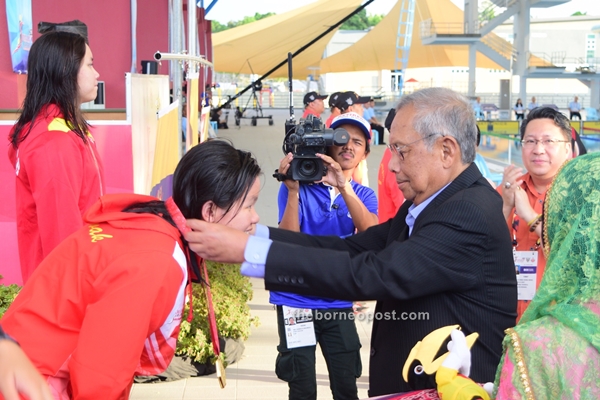 Adenan (right) placing gold medal on Chieng for winning the women's 800m freestyle category. 