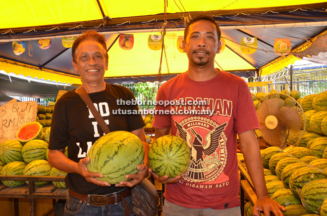 Hamdan (right) and his father Shamsuddin at their watermelon stall at the Fama Market in Sipitang.