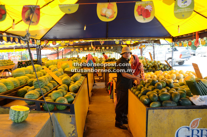 Customers selecting watermelons at Shamsuddin’s watermelon stall at the Fama Market in Sipitang.