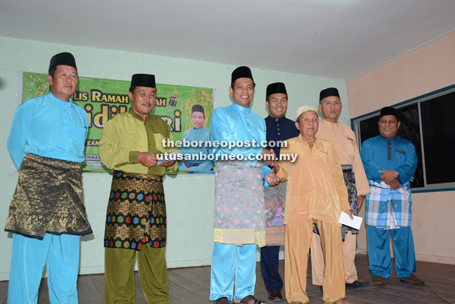 Dr Abdul Rahman (third left), flanked by Bungsu (second right) and Sufian, presenting a Raya gift to a senior citizen.